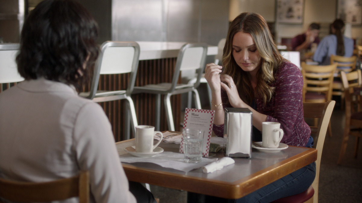 Jo sits sadly at a diner table